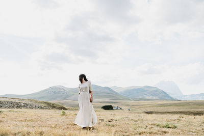 Rear view of woman standing on field against sky