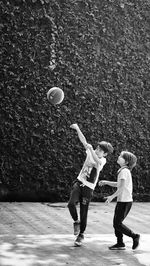 Siblings playing basketball on footpath