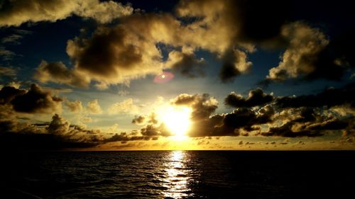 Scenic view of sea against cloudy sky at sunset