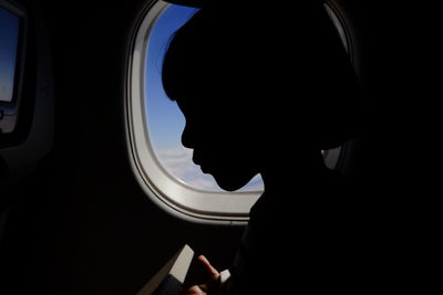 Close-up silhouette boy by airplane window