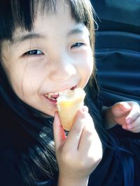 Close-up portrait of a smiling girl holding ice cream