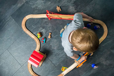 High angle view of boy playing with miniature train at home