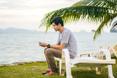 Side view of young man sitting on beach