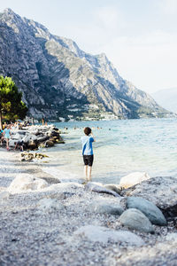 Rear view of man standing on rock by sea