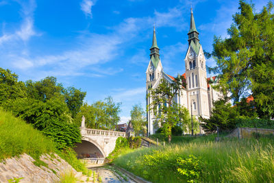 Arch bridge amidst trees and buildings against sky