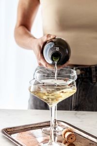 Midsection of woman holding wineglass on table