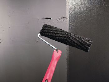 Close-up of hand holding black hanging against wall