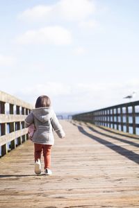 Rear view of girl walking on pier