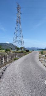 Electricity pylon by road against sky