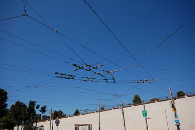 Low angle view of power lines against clear blue sky