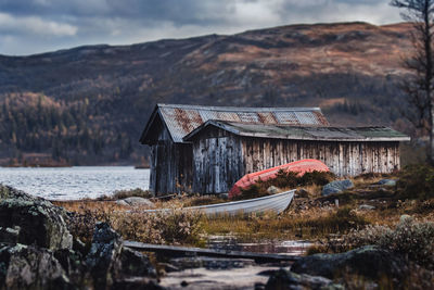 Abandoned house by lake against sky