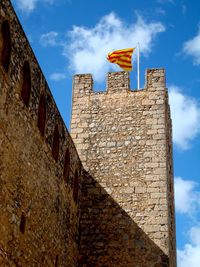 Medieval stone castle with flag of catalonia against sky
