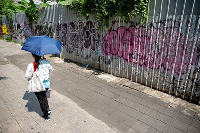 Rear view of woman walking on wet footpath during rainy season