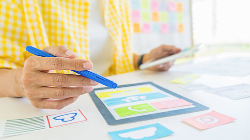 Midsection of man holding paper with text on table