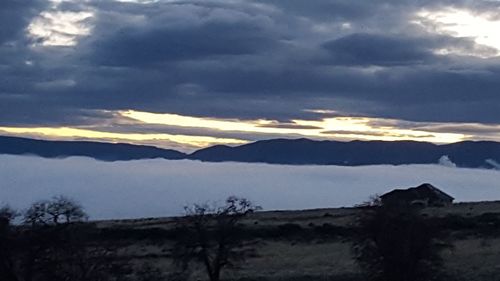 Scenic view of landscape against dramatic sky at sunset