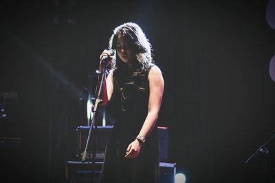 Young woman singing during concert 