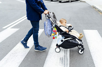 Man with baby stroller crossing road in city