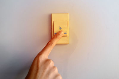 Midsection of person holding paper against wall at home