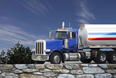 Truck moving on road against blue sky during sunny day