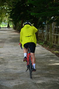 Rear view of man riding bicycle on road