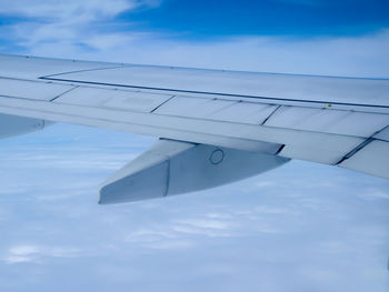 Close-up of airplane wing against cloudy sky
