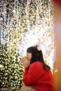 Side view of woman looking away against christmas tree