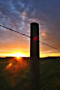 Scenic view of landscape against cloudy sky at sunset