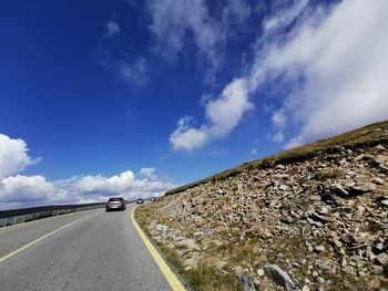 Car on road against cloudy sky