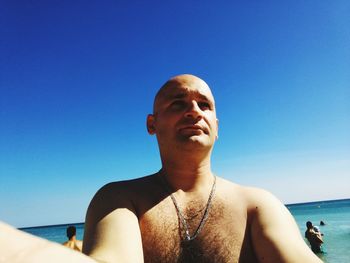 Mid adult man by sea against clear blue sky