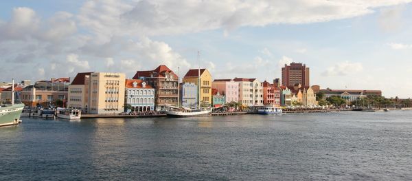 Buildings by river against sky in city