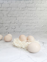 Close-up of eggs on table against white wall