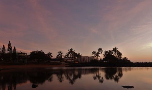 Scenic view of lake by trees against sky during sunset