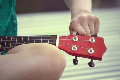 Close-up of hands tuning guitar