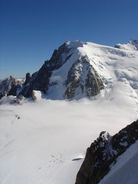 Scenic view of snow covered mountains against clear blue sky