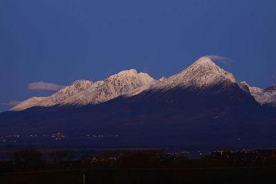 Scenic view of snowcapped mountains against blue sky