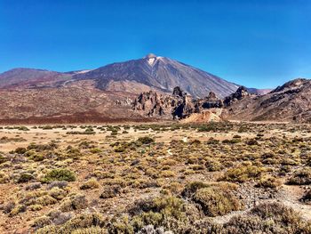 Scenic view of desert against clear blue sky