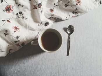 Directly above shot of coffee and spoon by pillow on bed