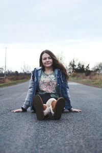 Portrait of young woman sitting on road