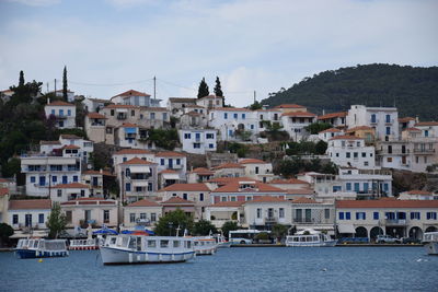 Sailboats in sea by townscape against sky