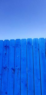 Low angle view of wooden fence against blue sky