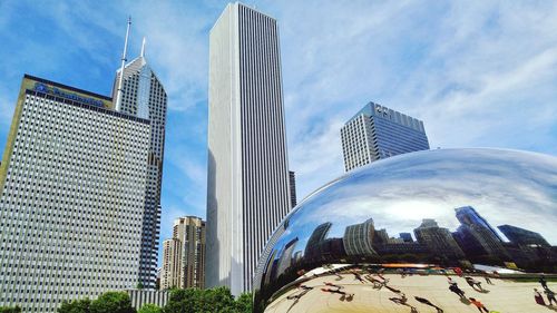 Low angle view of skyscrapers against cloudy sky