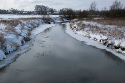 Frozen river against sky during winter