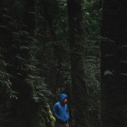 Man wearing warm clothing while standing amidst trees in forest