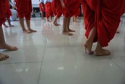 Low section of men wearing red dhotis while dancing on tiled floor