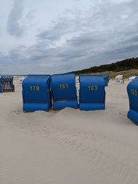 Hooded chairs on beach against sky