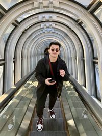 Portrait of young woman standing on escalator