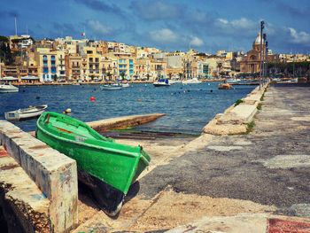 Boats moored on sea by buildings in city against sky