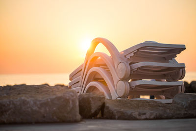 White plastic sun loungers at the beach on vacations at sunset