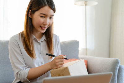 Young woman writing in book at home