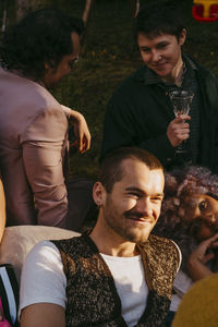 Portrait of smiling friends sitting on street